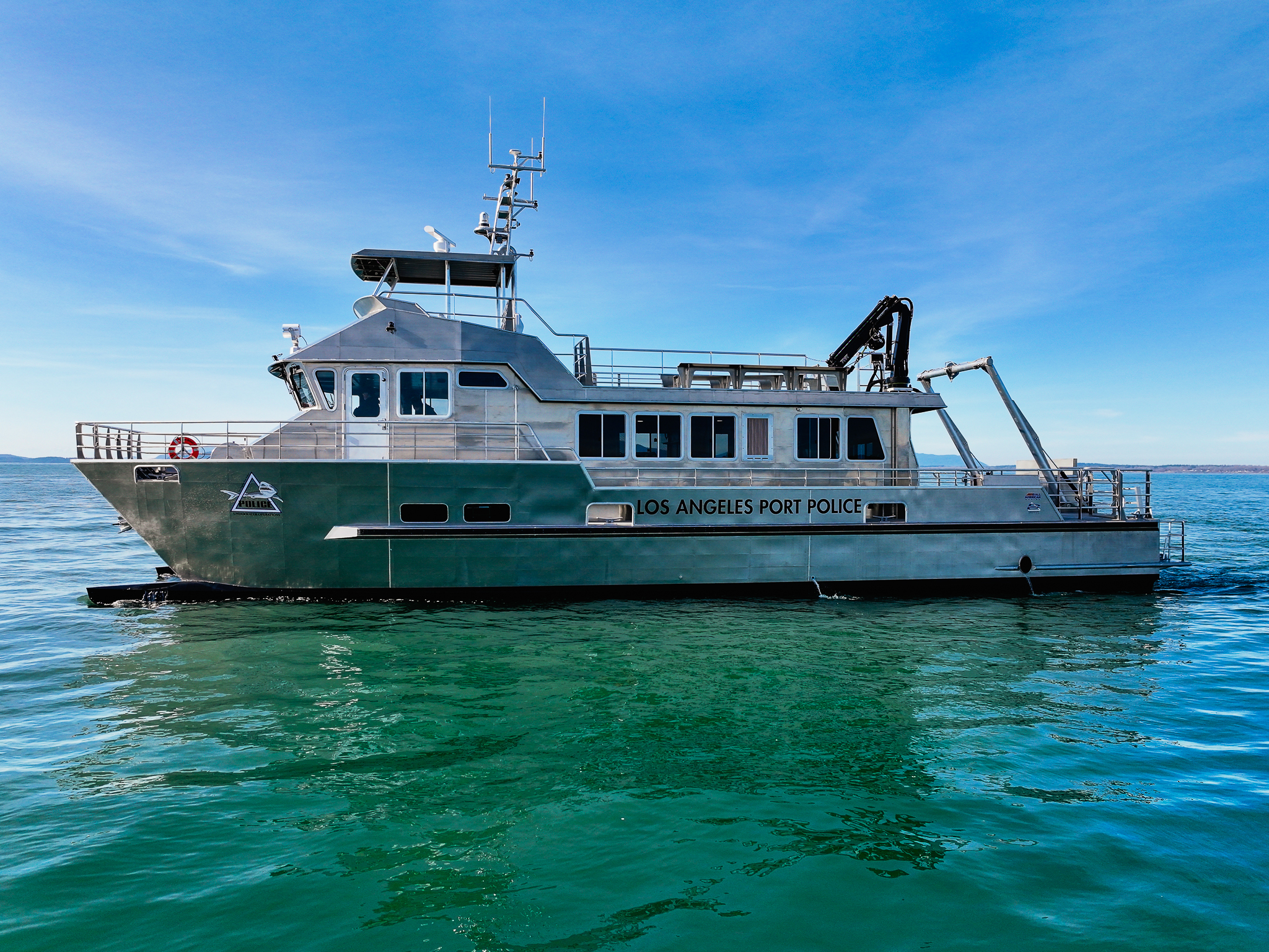 Los Angeles Port Police patrol boat on calm water with a clear blue sky above.